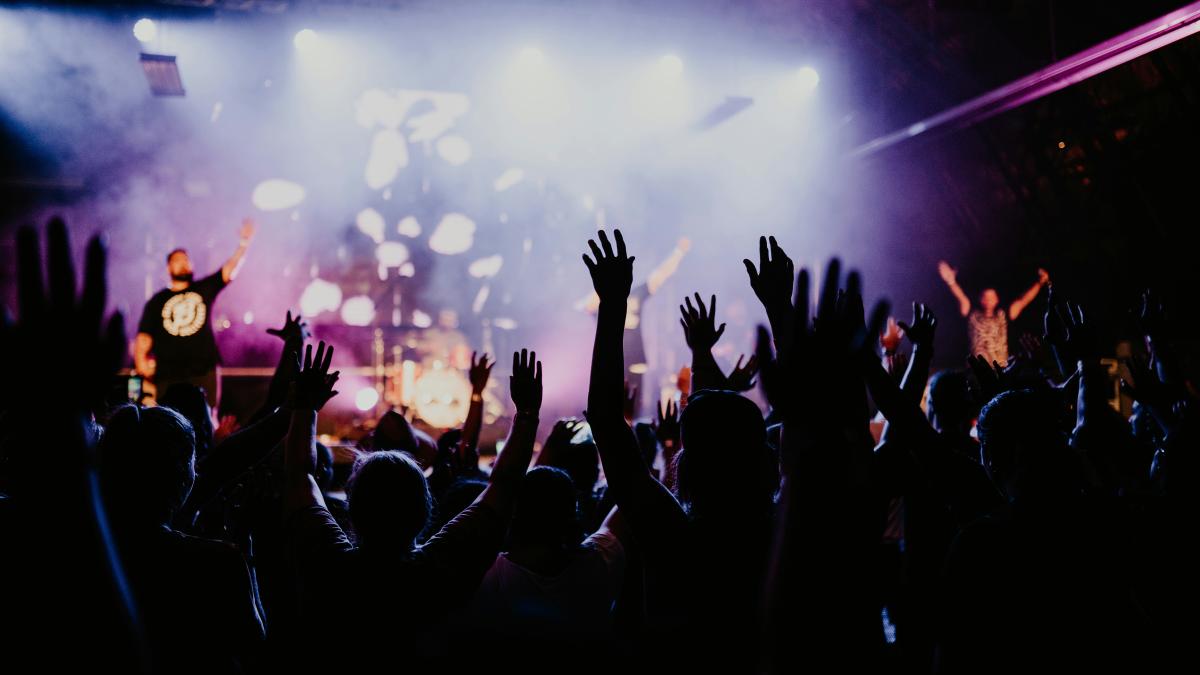 people raising their hands in front of crowd