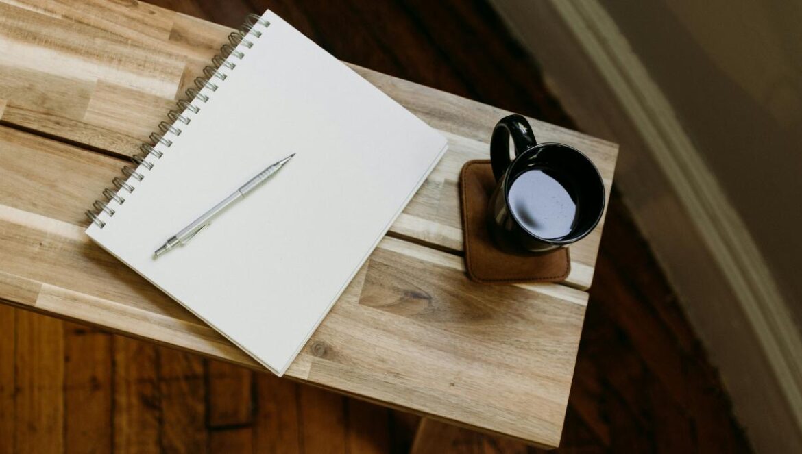 a cup of coffee and a pen on a wooden table
