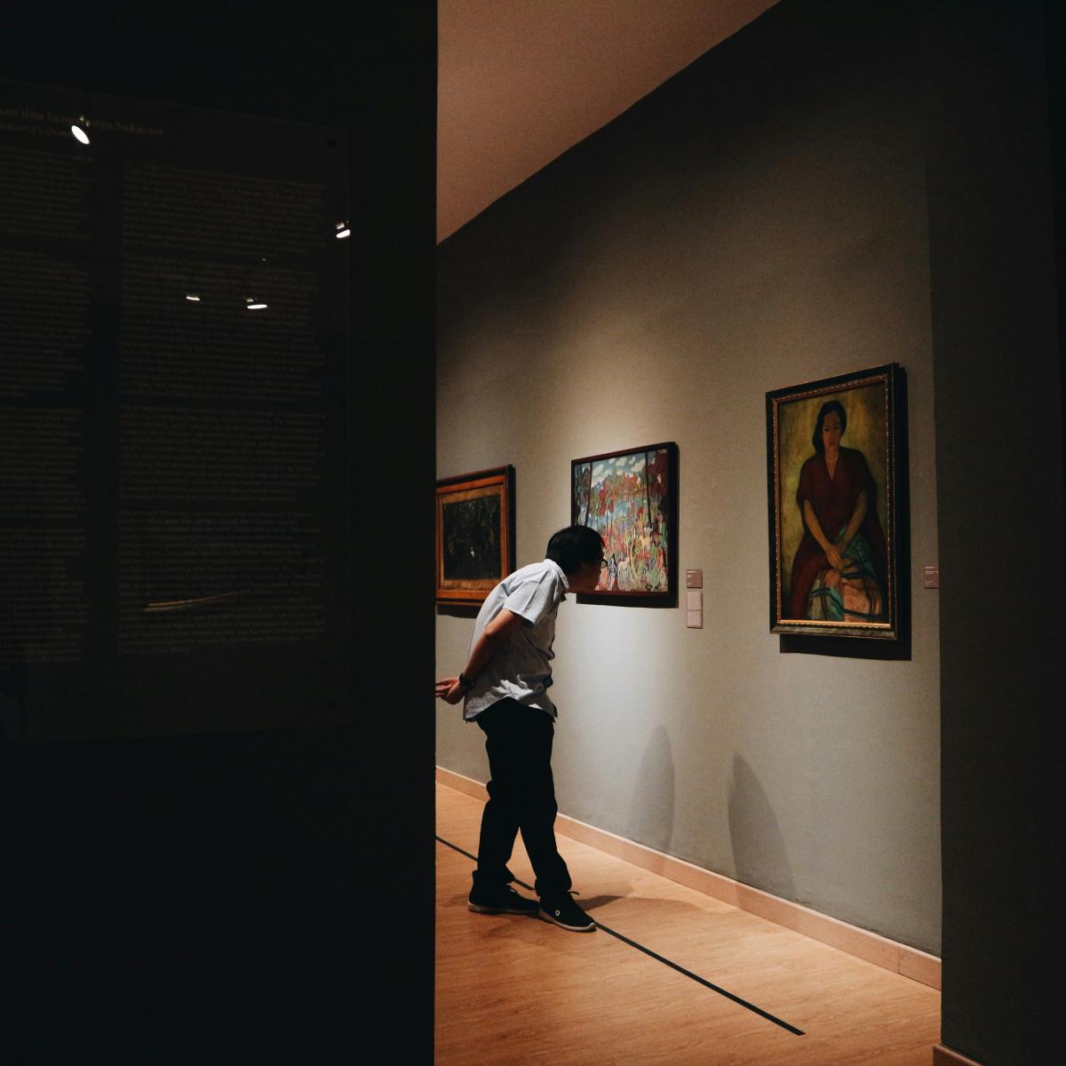 man wearing white shirt standing beside painting screenshot