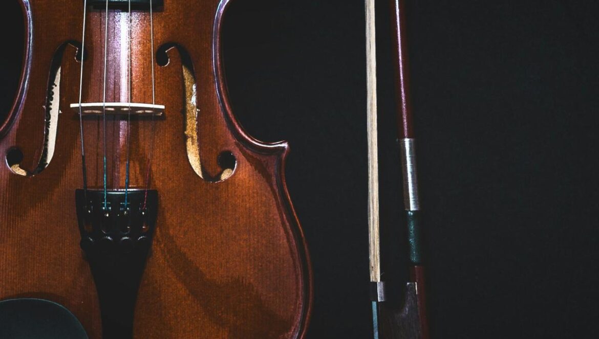 brown violin with bow in black background