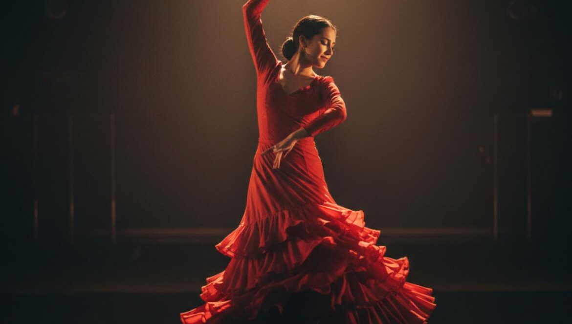 Une danseuse de flamenco en robe rouge effectuant un mouvement expressif sur une scène sombre éclairée par un projecteur.