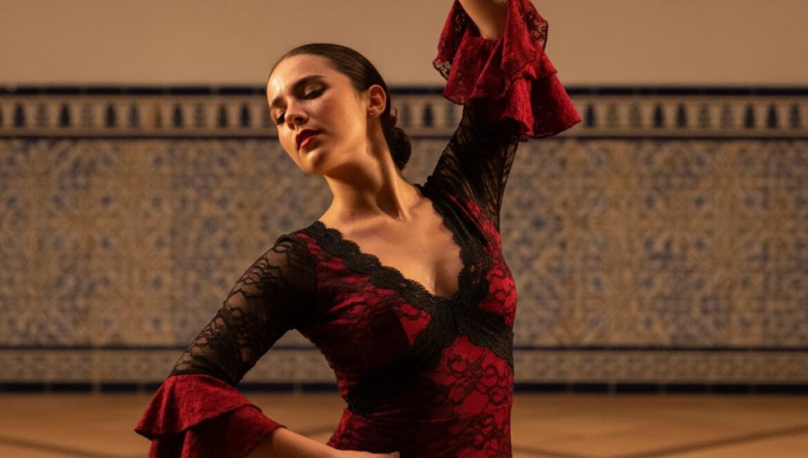 Danseuse de flamenco sur une petite scène andalouse, lumière chaude, murs blanchis et azulejos.