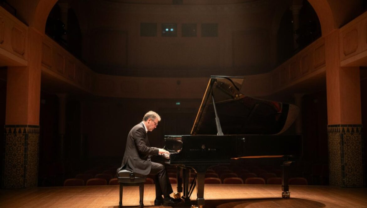 Pianiste jouant seul au piano à queue sur une scène intimiste, éclairée d’une lumière chaude dans un petit théâtre andalou.